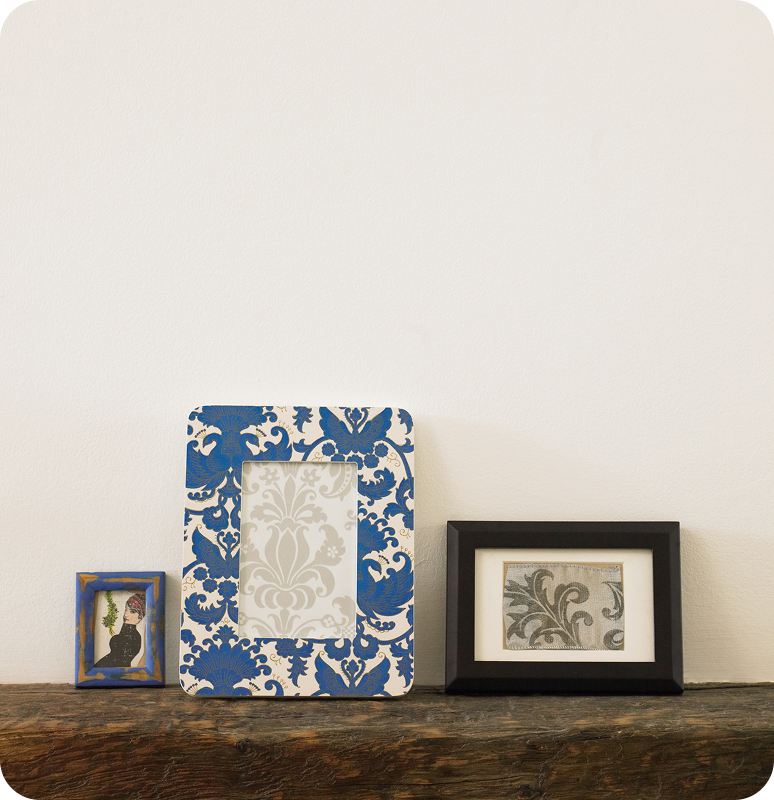 Three framed artworks displayed on a wooden surface against a beige wall.